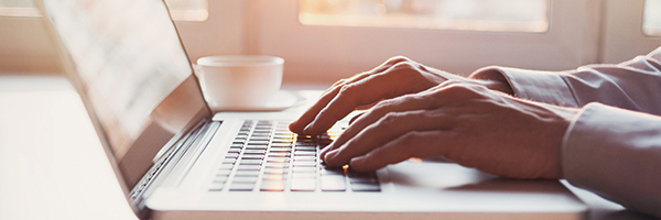 Primer plano de manos escribiendo en un teclado de computadora portátil.