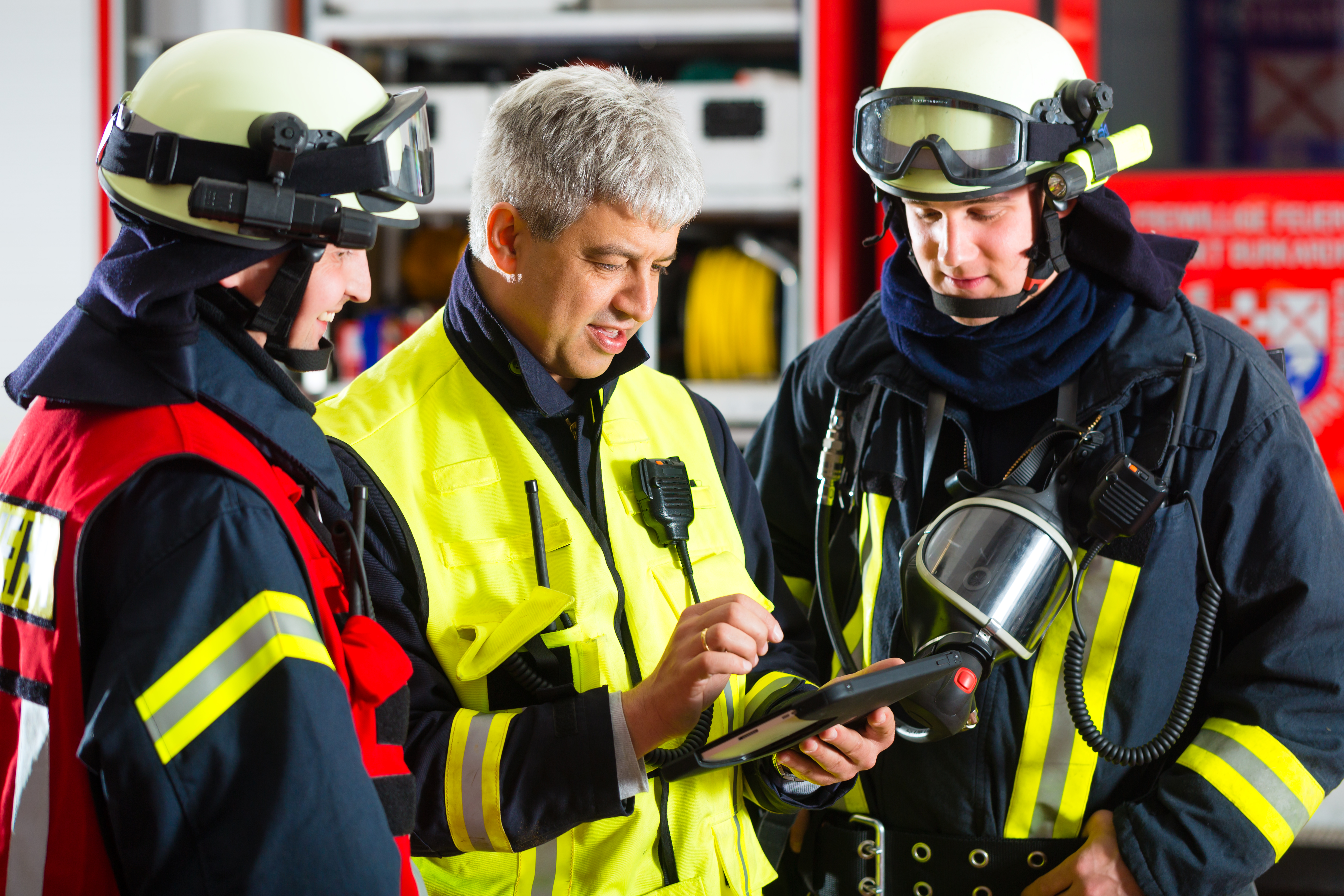 Bomberos mirando a una tableta que se gestiona y protege mediante la solución SOTI ONE Platform